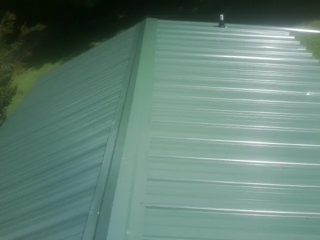 New green metal panels meeting at the ridge of a roof — Flat Roof Repair work by our crew in Sekiu