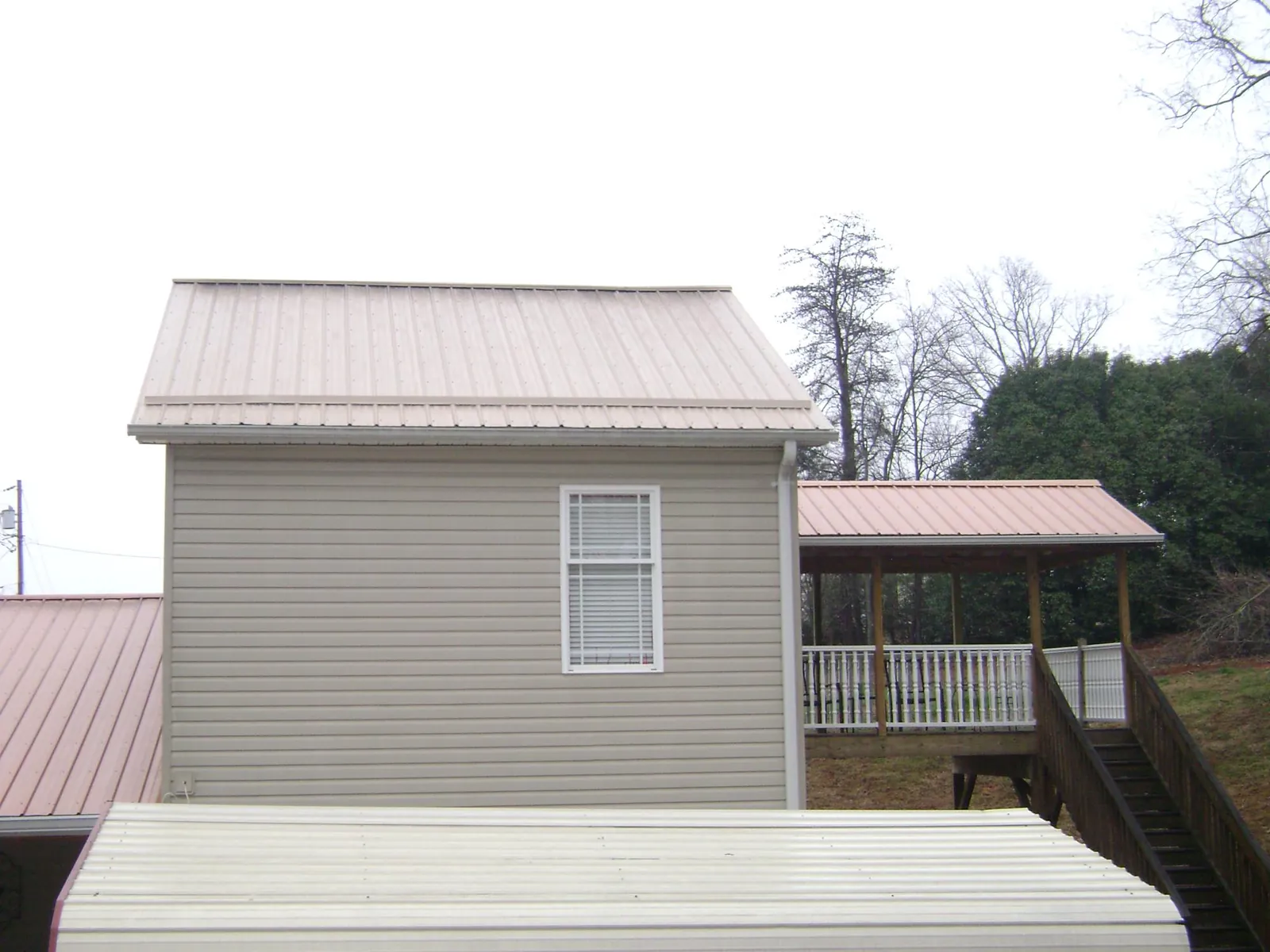 Tan metal roofs on a two story addition and attached porch, from a Roof Replacement job in Sekiu