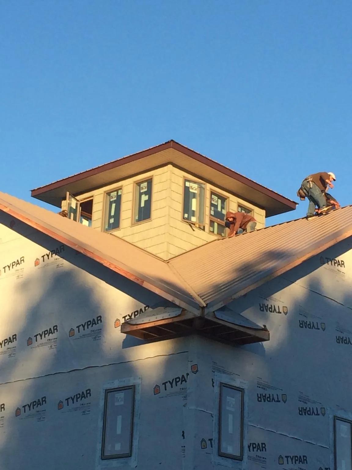 Roofers working around a rooftop cupola on a new metal roof at sunset — Roof Waterproofing in Sekiu by Roofing Brothers